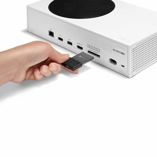 Hand inserting storage expansion card into game console.